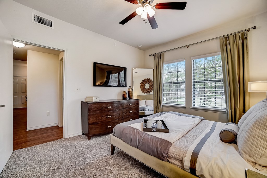 the master bedroom features a king sized bed and a flat screen tv