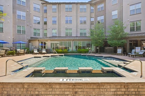A large swimming pool in front of a building with a sign that says "No Diving".