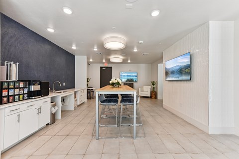 A modern kitchen with a dining table and chairs in the center.