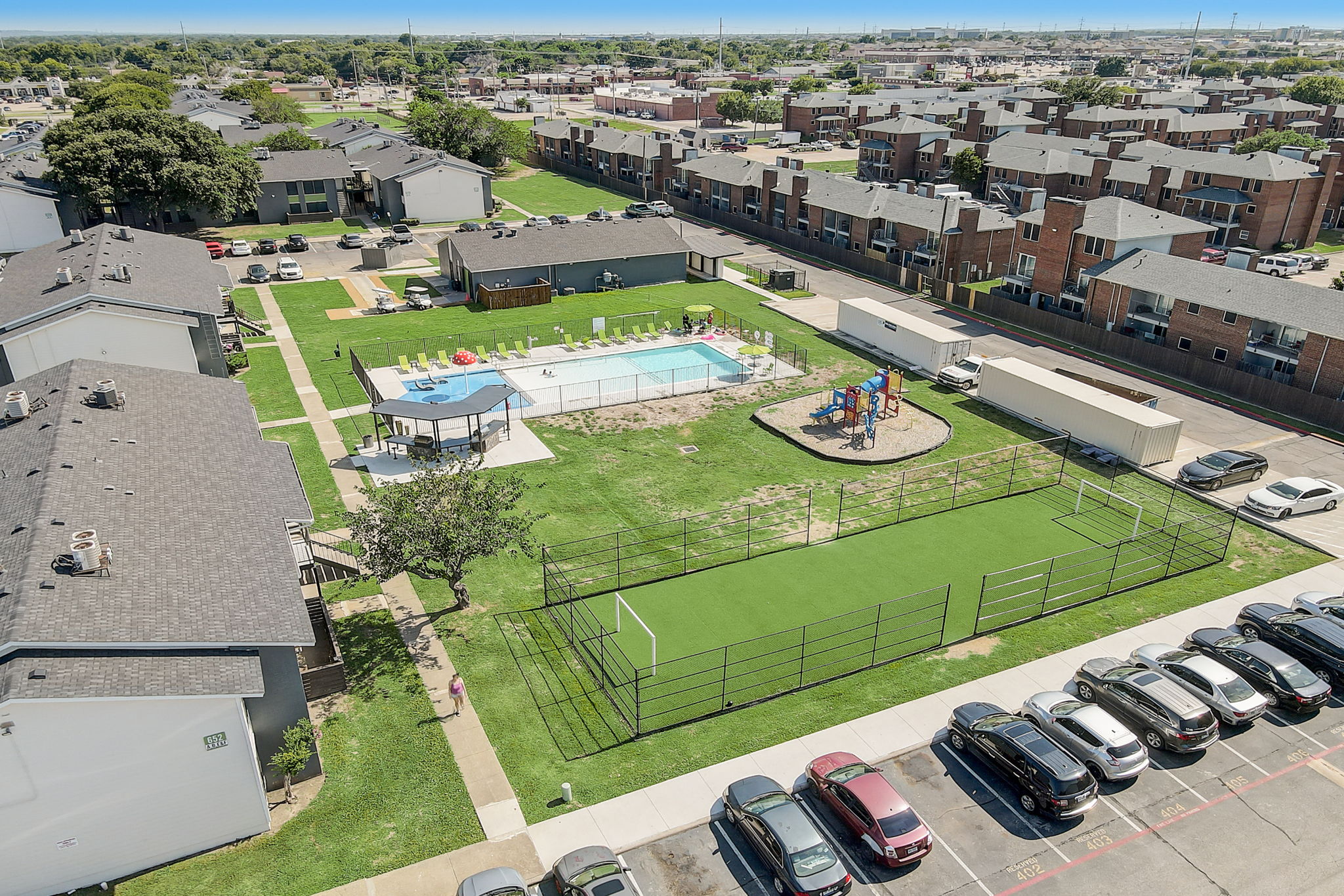 an aerial view of a tennis court and pool in a residential neighborhood