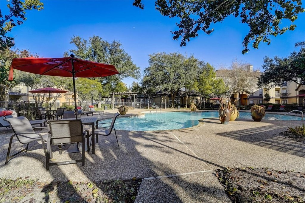 a swimming pool with tables and umbrellas next to it