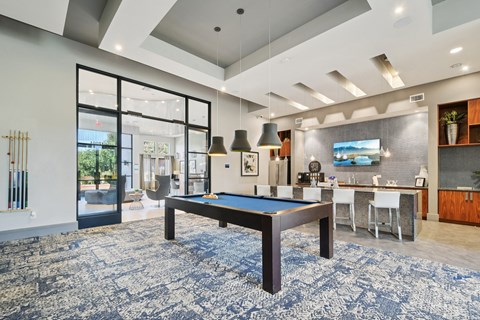 A pool table is in the middle of a room with a blue carpet.