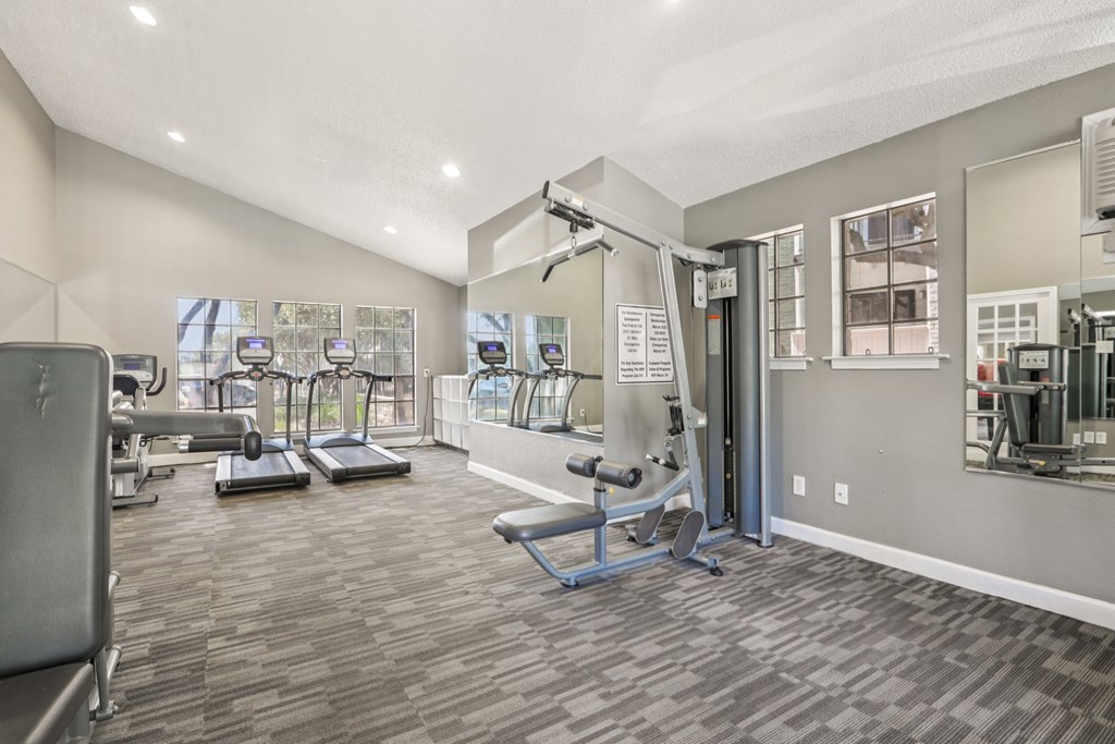 A gym with a variety of equipment including treadmills, weights, and exercise machines.