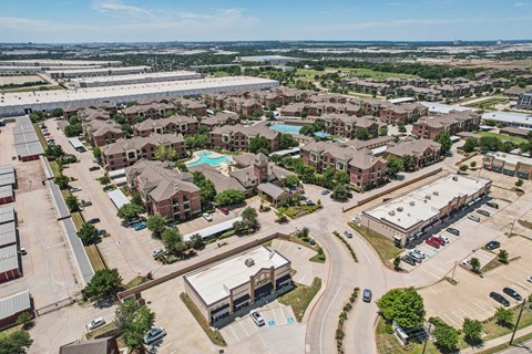 A bird's eye view of a residential area with houses, roads, and vehicles.