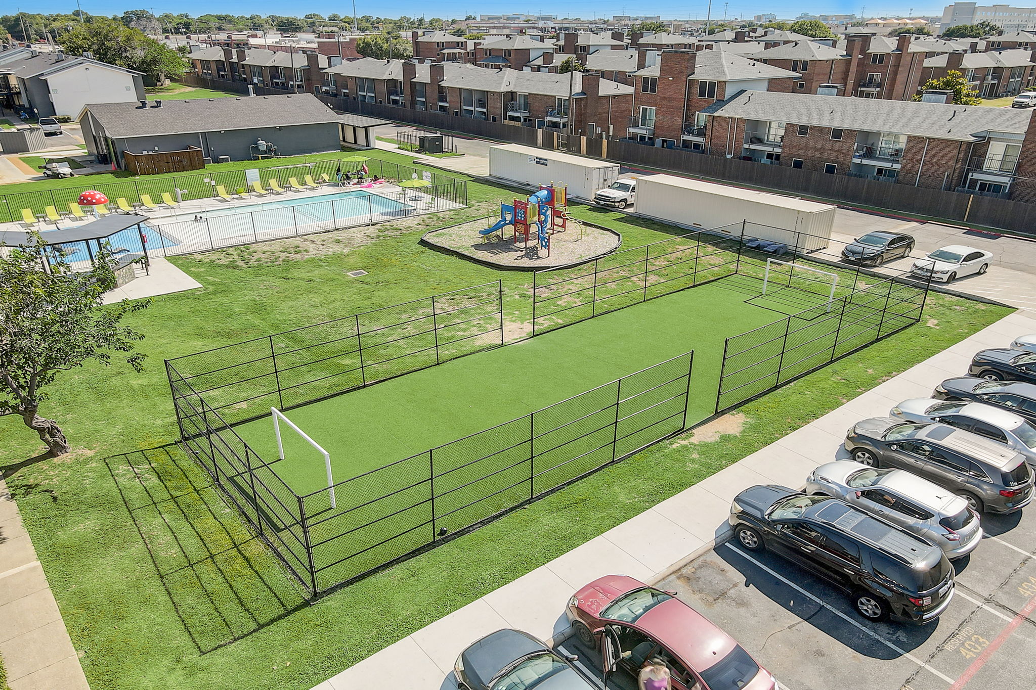 an aerial view of a fenced in grassy area with a swimming pool and playground