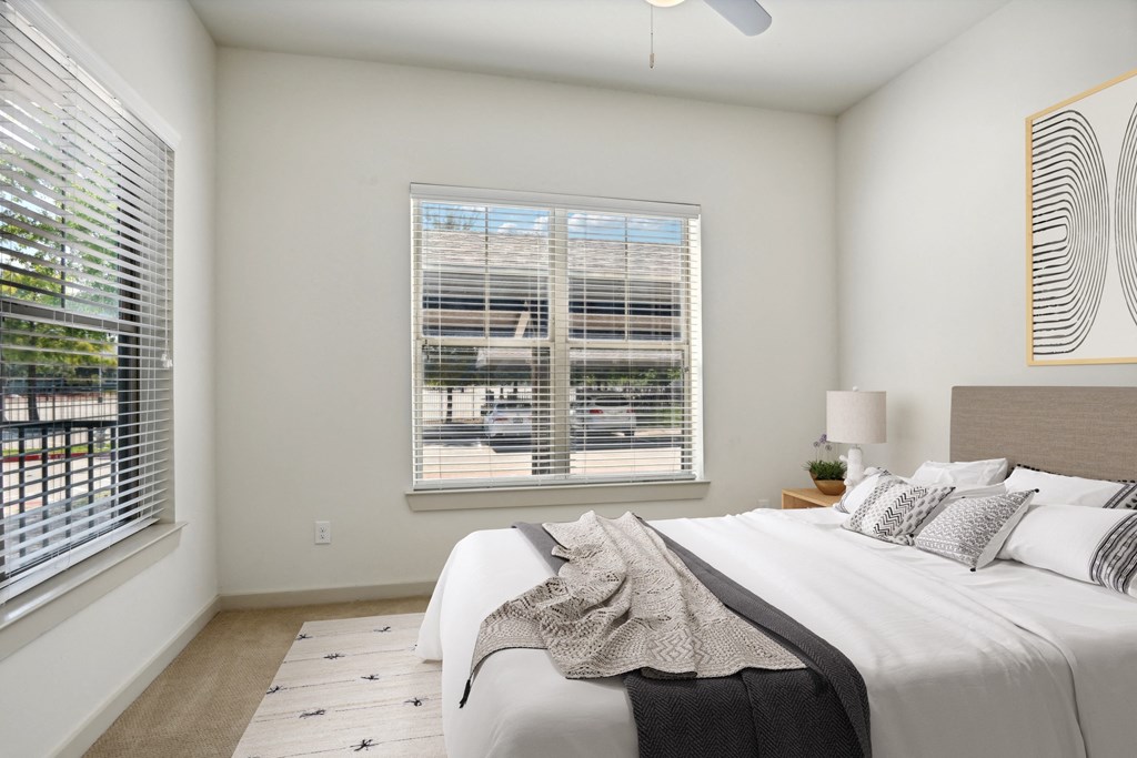 a bedroom with a large bed and two windows