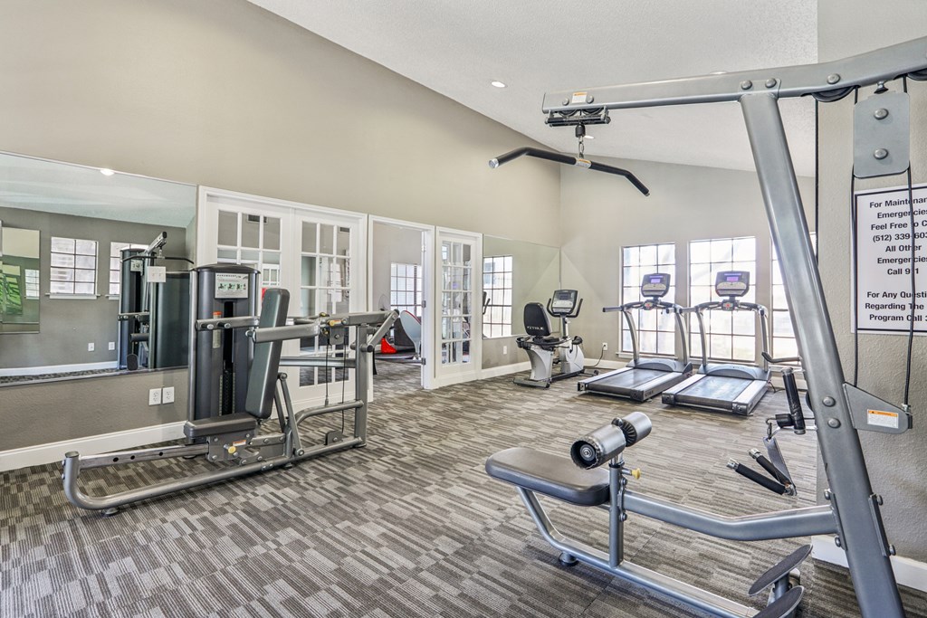 A gym with a variety of equipment including treadmills, weights, and a rowing machine.