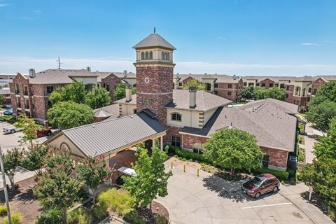 A large building with a tower is surrounded by other buildings and trees.
