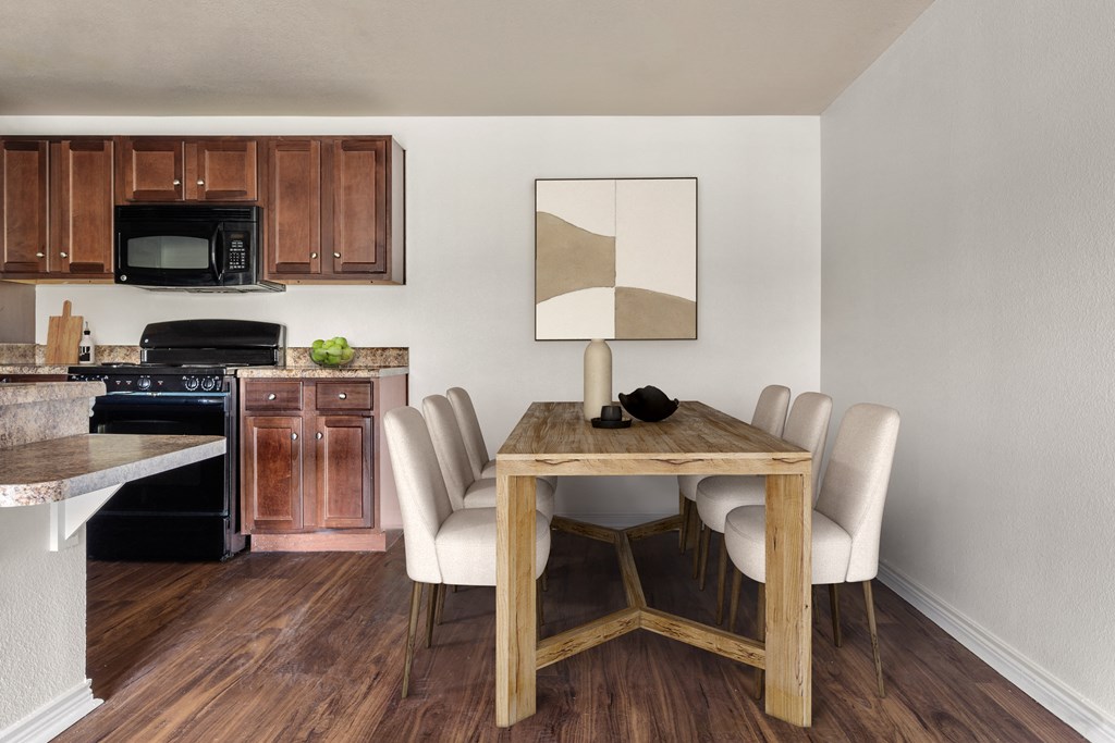 a dining room with a table and chairs and a kitchen in the background