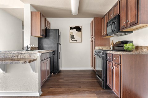 a kitchen with wooden cabinets and a black stove and refrigerator