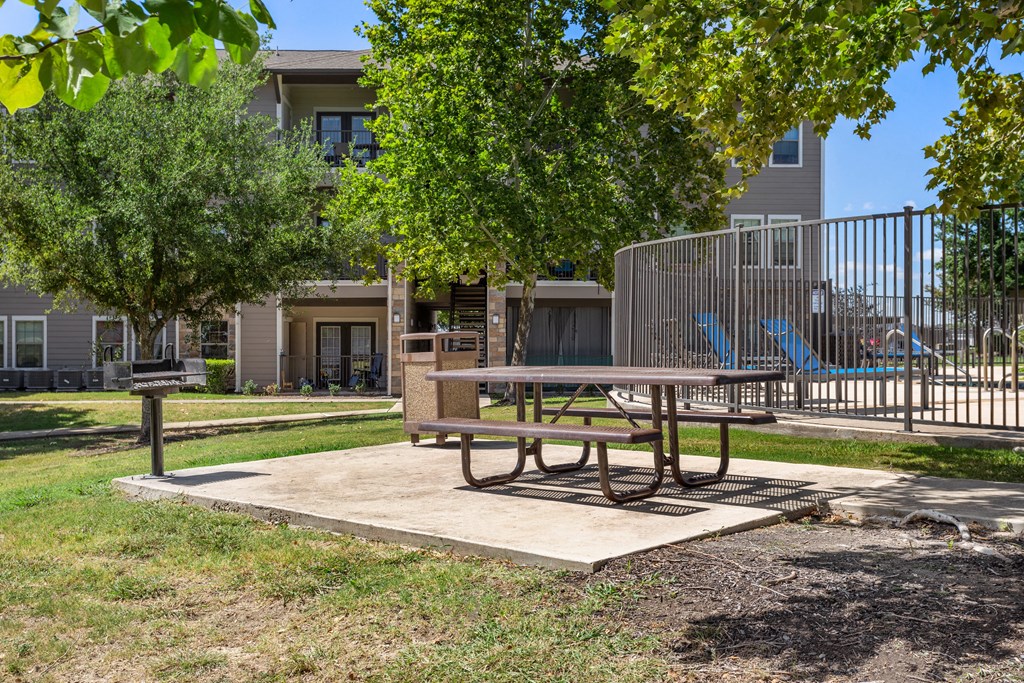 a picnic table in a park with a playground in the background