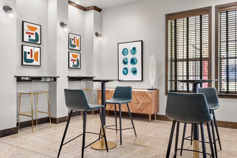 Social nook with bar-height tables, modern stools, and framed artwork accents.