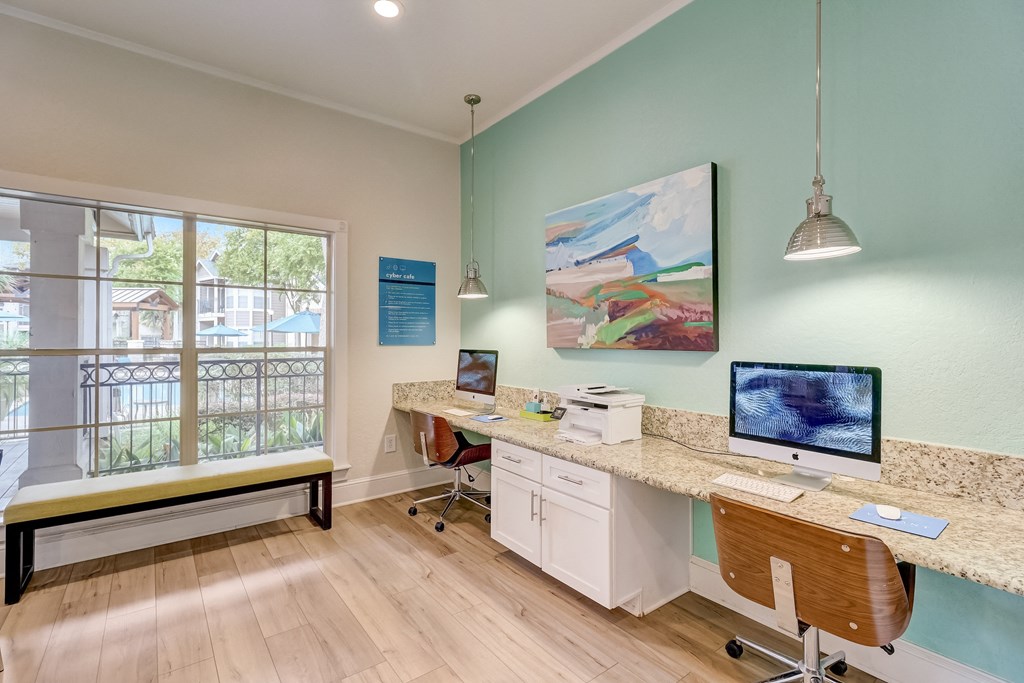 an office with a desk with two computers and a window