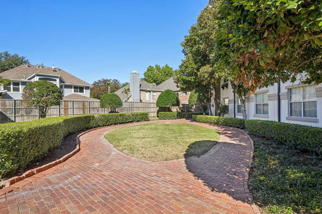 A residential area with a brick pathway and houses on either side.