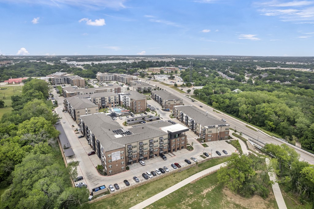 an aerial view of an apartment complex with trees and a highway