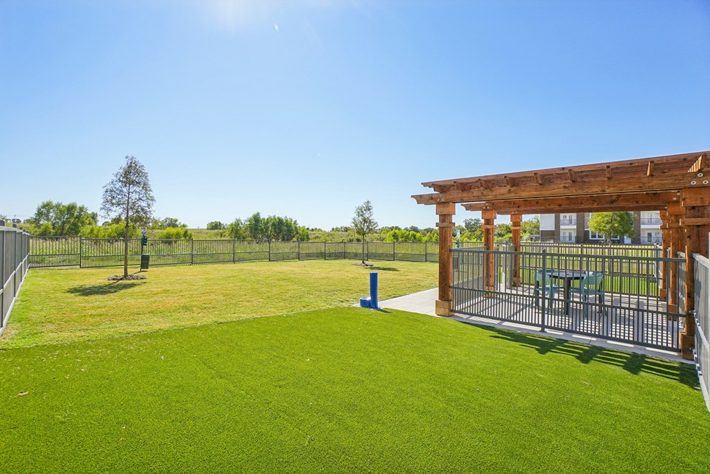A sunny day at a park with a wooden structure and a fence.
