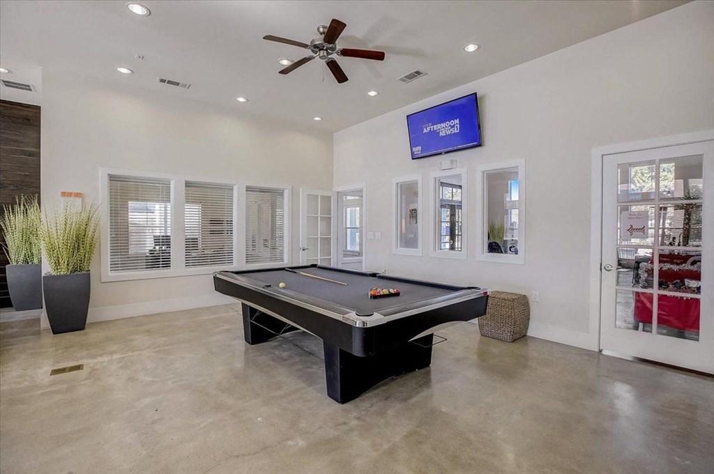 a game room with a pool table and a ceiling fan