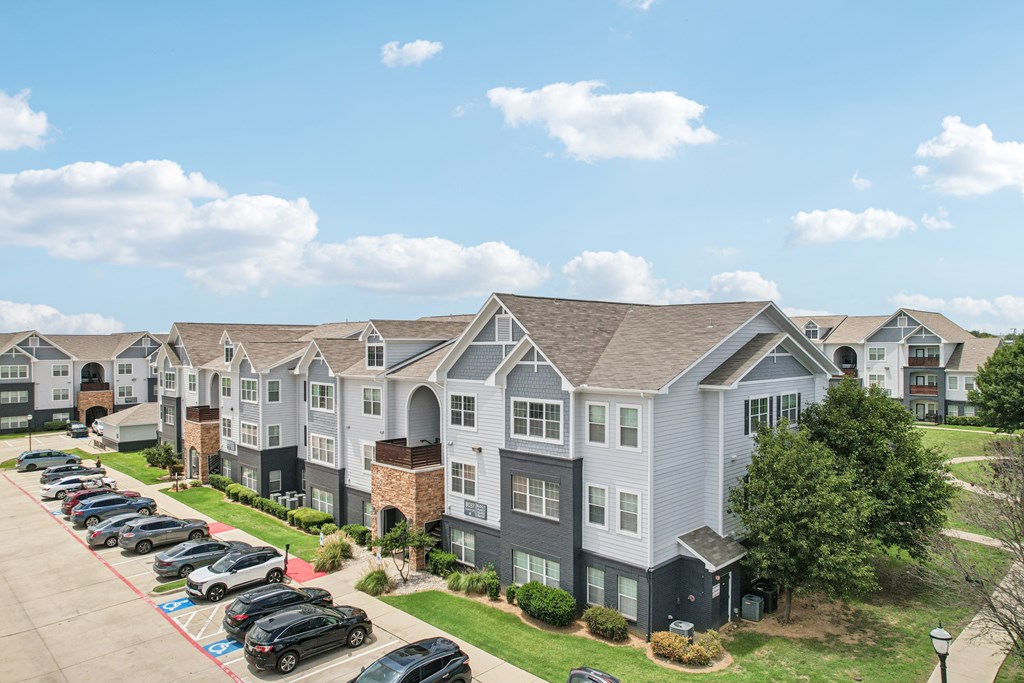 A row of townhouses with a parking lot in front.