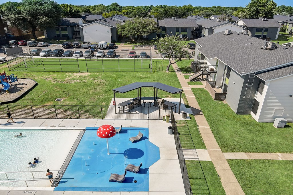 an aerial view of a backyard with a pool and volleyball court