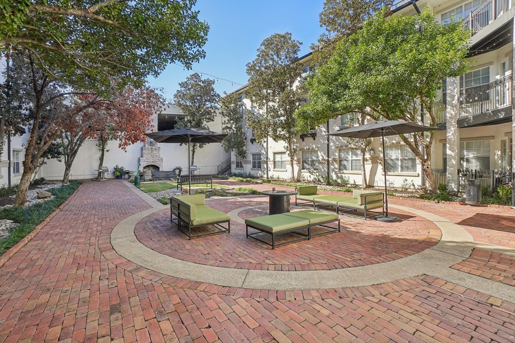 A courtyard with a circular brick patio and benches.