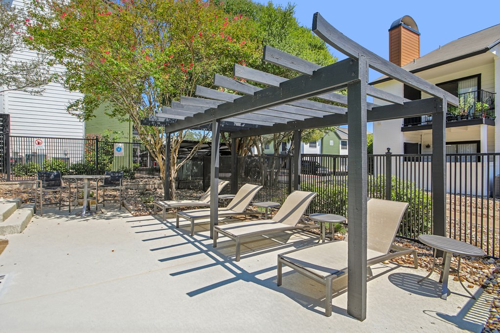 A patio with a table and chairs under a pergola.
