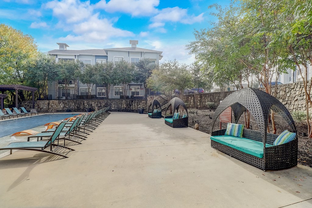 a resort style swimming pool with lounge chairs and a hotel in the background