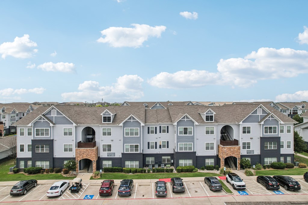 A large apartment complex with a parking lot in front.