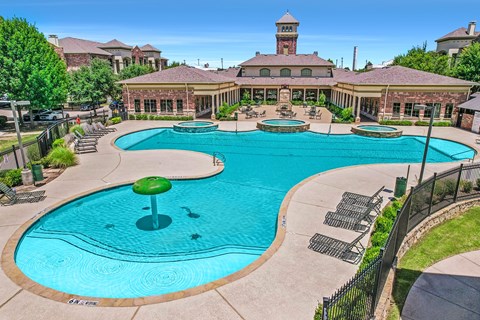 A large swimming pool with a water slide and a building in the background.