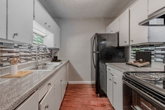 an empty kitchen with white cabinets and a black refrigerator