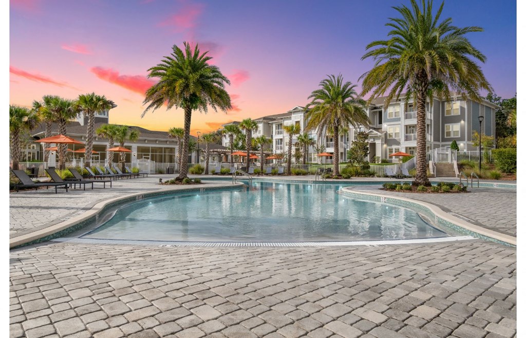 a large swimming pool with palm trees in front of an apartment building