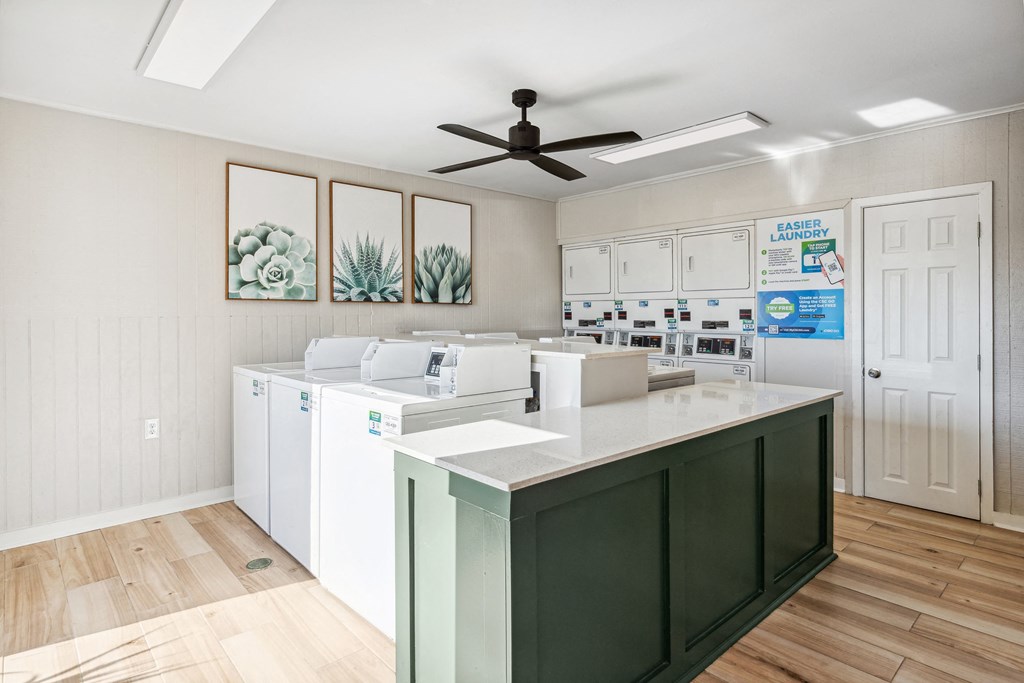 a laundry room with white cabinets and a green island with white appliances