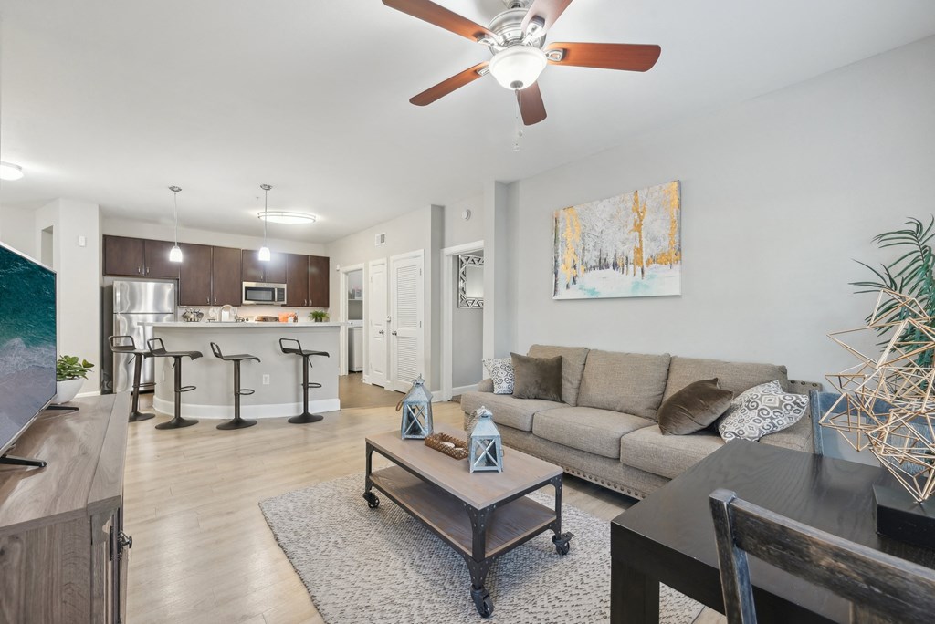 A living room with a couch, coffee table, and a ceiling fan.