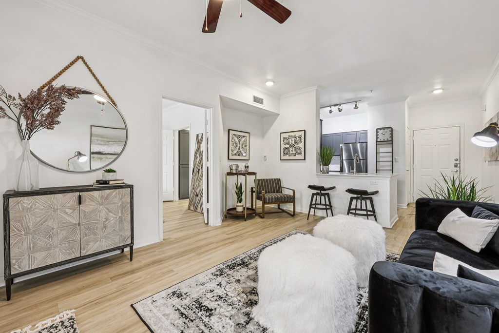 A living room with a black and white rug, a black couch, and a wooden cabinet.
