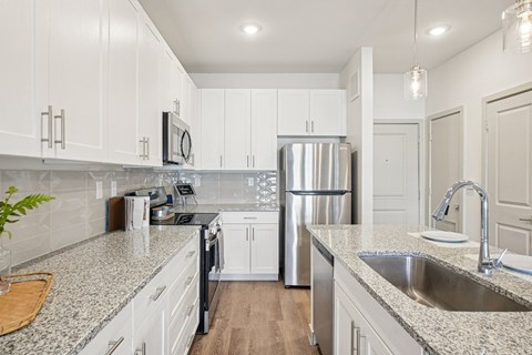 A kitchen with white cabinets and a granite countertop.