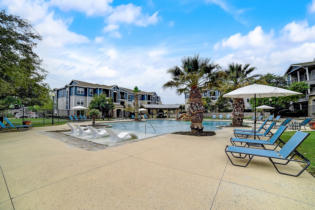 a large pool with lounge chairs and umbrellas at the enclave at woodbridge apartments in