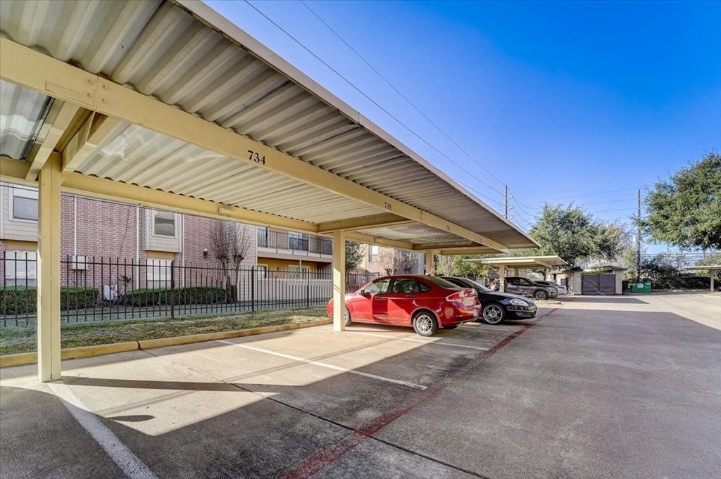 a parking lot with two cars parked under awning