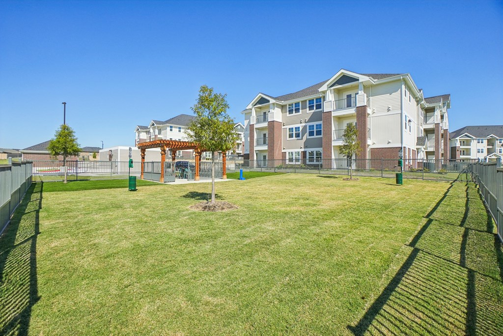 A large grassy area in front of a multi-story apartment building.