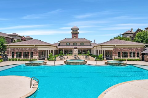 A large swimming pool in front of a building with a tower.