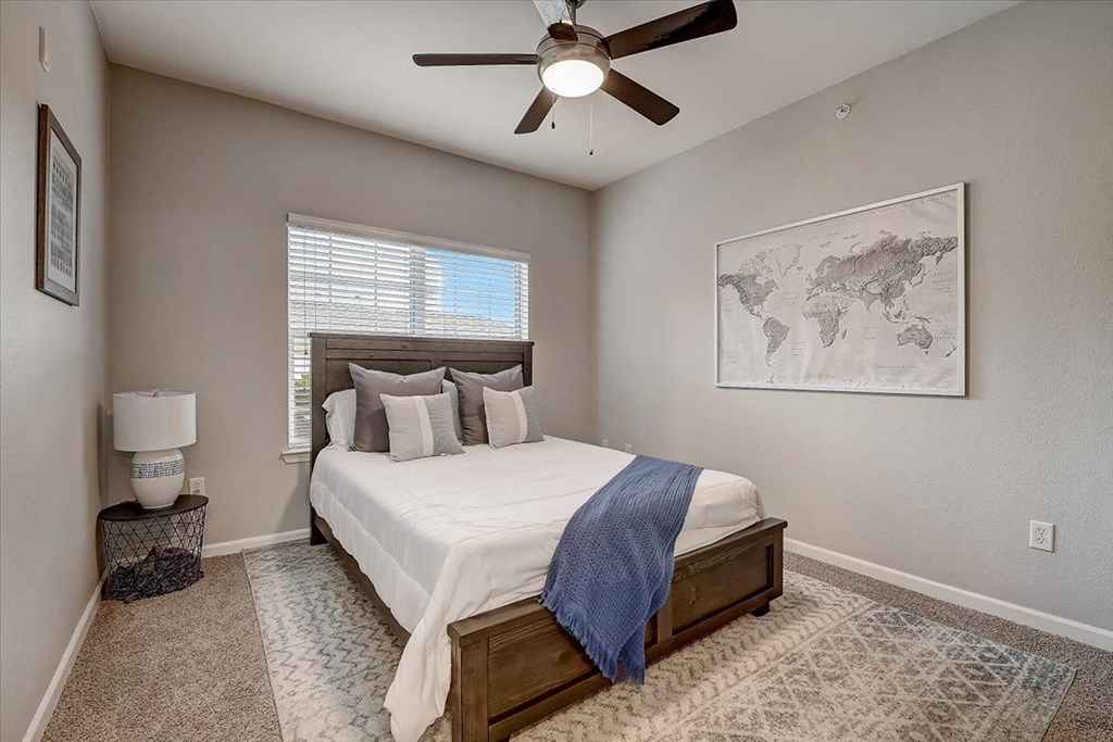 a bedroom with a ceiling fan and a large window