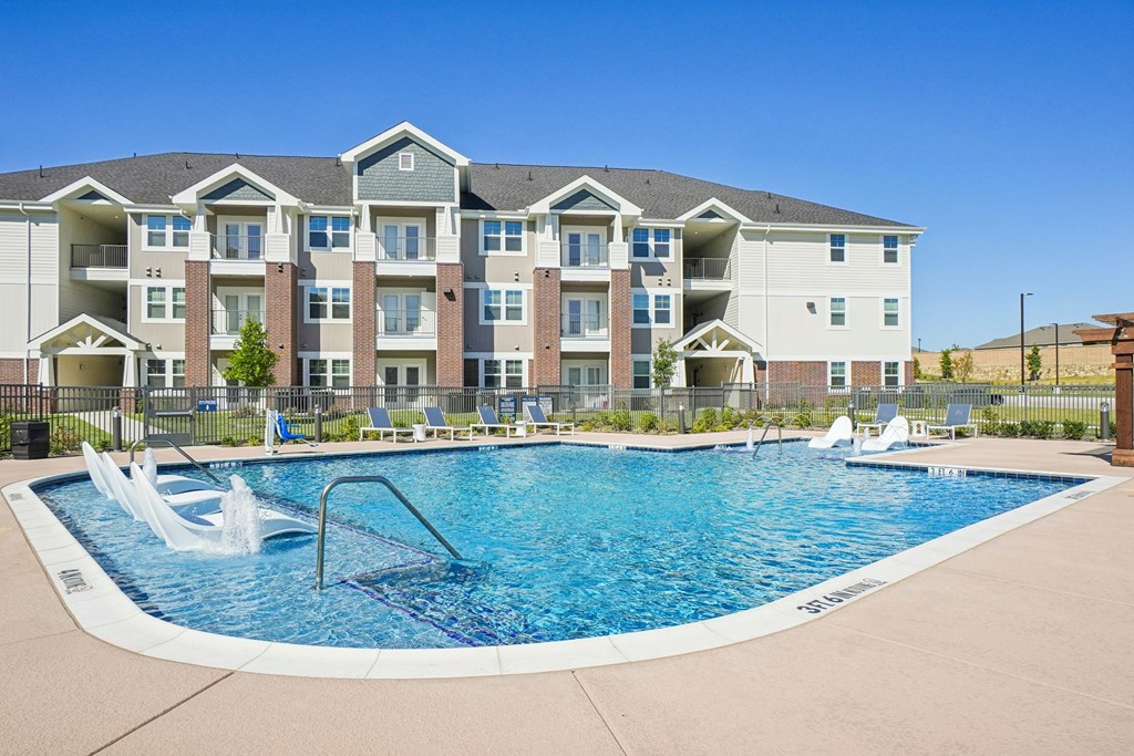 A large swimming pool in front of a multi-story apartment building.