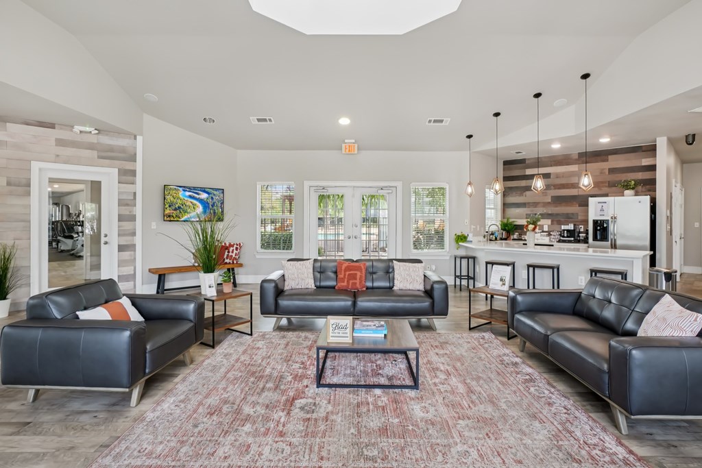 A living room with a large rug and a coffee table in the middle.