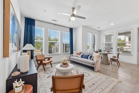 A living room with a couch, chairs, and a table with a vase on it.