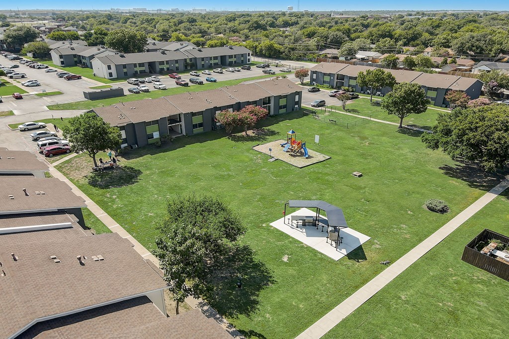 an aerial view of a park with a playground and buildings in the background