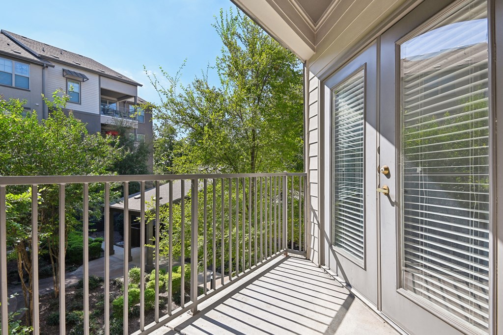 the view from the balcony of a home with a door to the yard