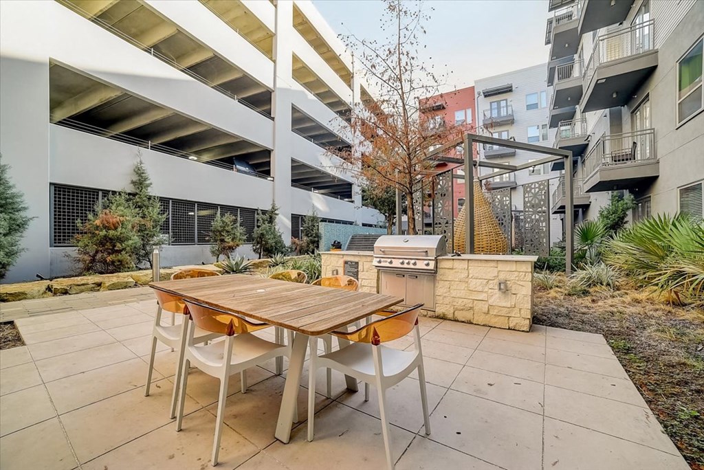 a patio with a table and chairs and a grill