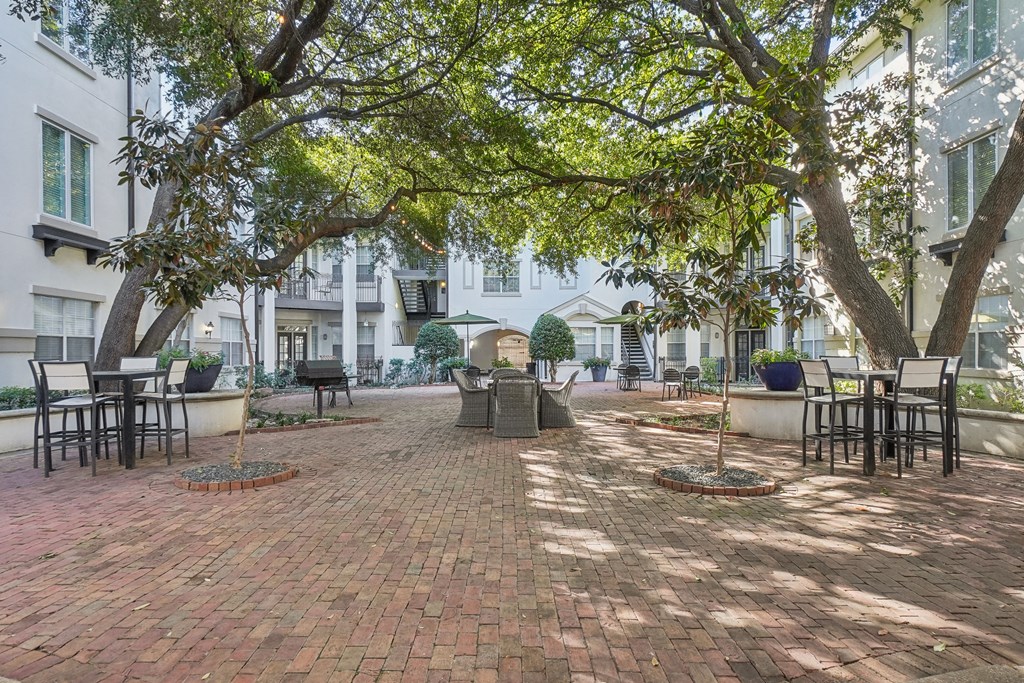 A courtyard with a brick floor and trees.