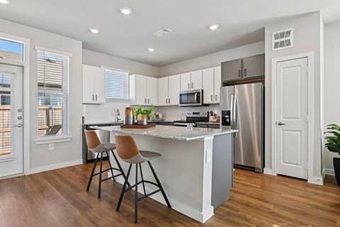 A kitchen with white cabinets and a wooden floor.