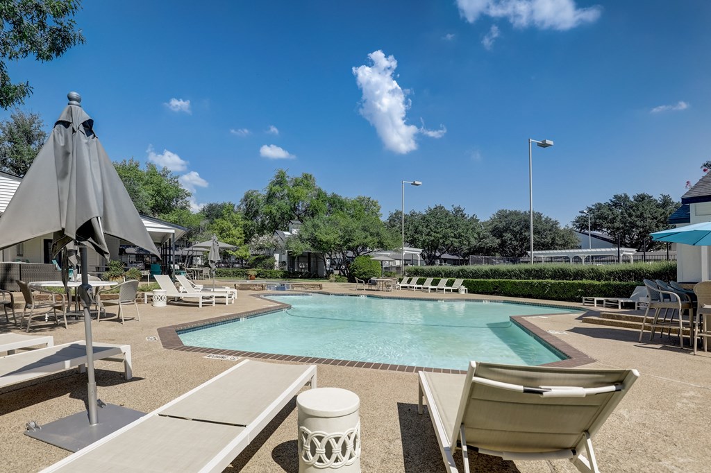 a swimming pool with chairs and umbrellas at the resort on a sunny day
