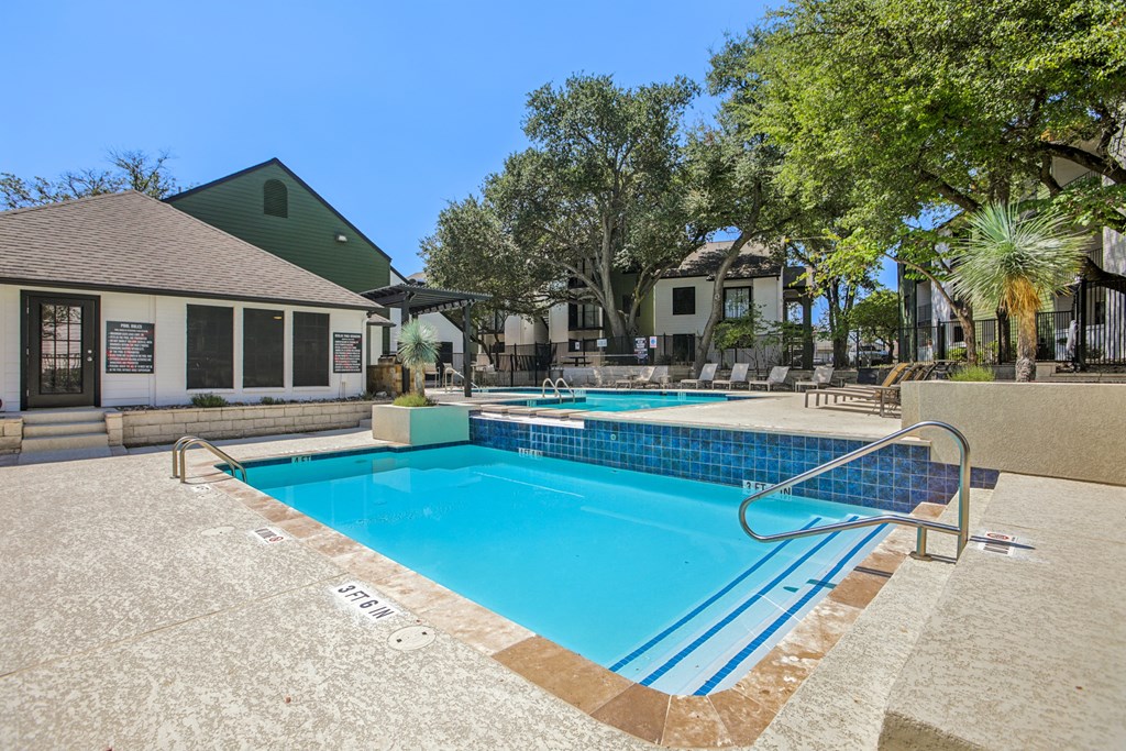 A swimming pool surrounded by a concrete floor and a metal railing.