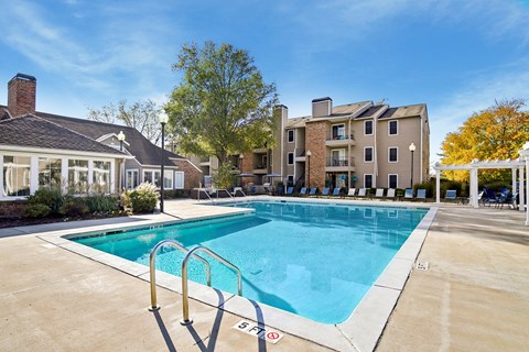 A swimming pool surrounded by a concrete floor and a metal ladder.